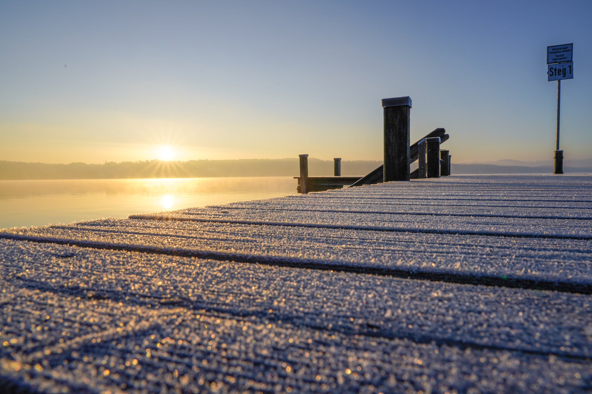 Vereister Steg am Starnberger See im Sonnenaufgang