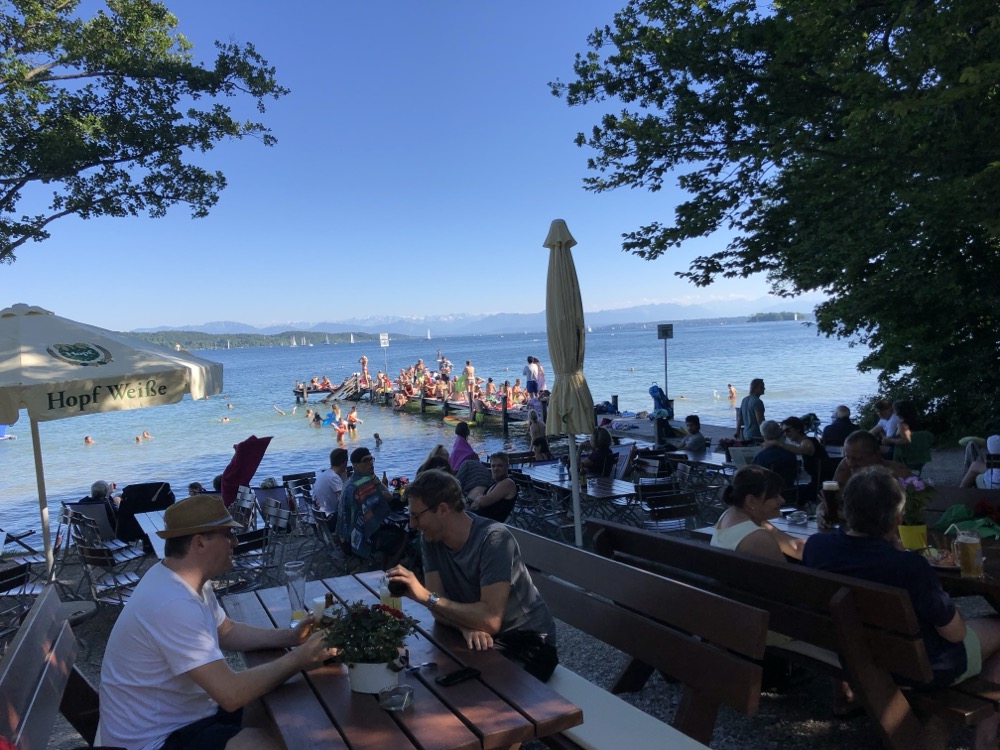 Biergarten am Starnberger See mit Blick auf Badegäste und Alpen
