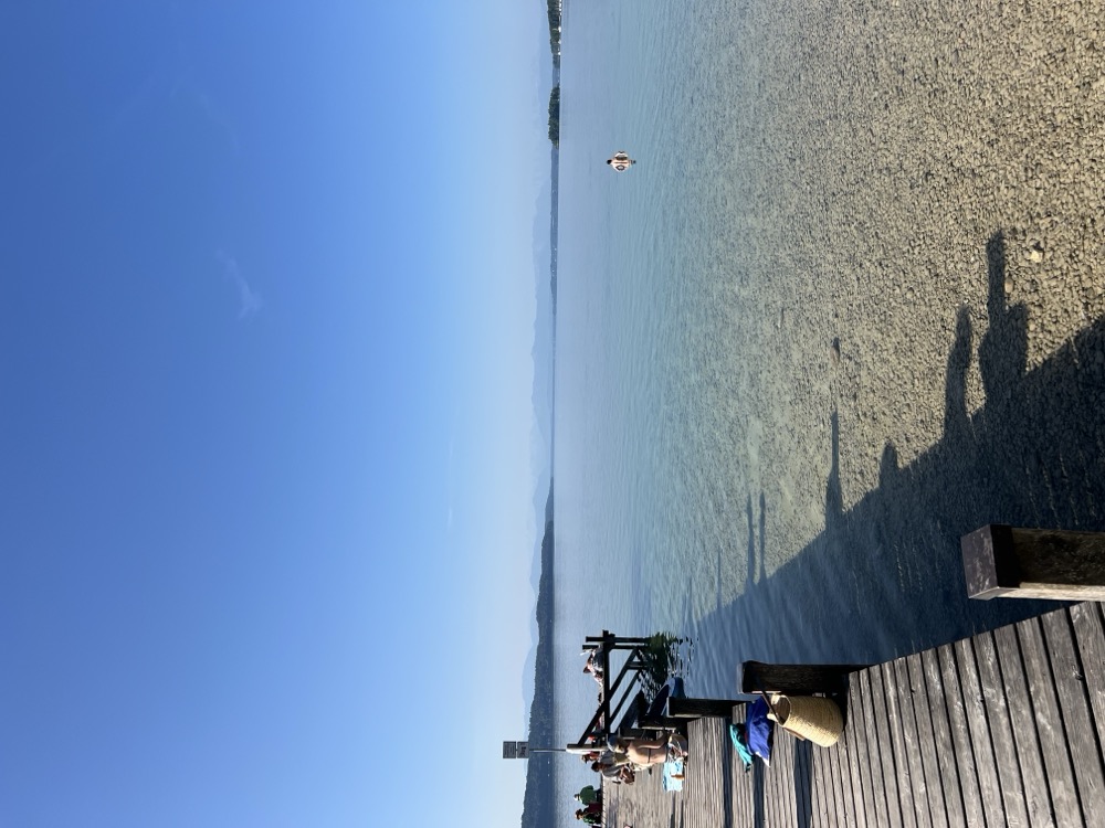 Blick vom Steg auf den weiten See bei klarem Himmel
