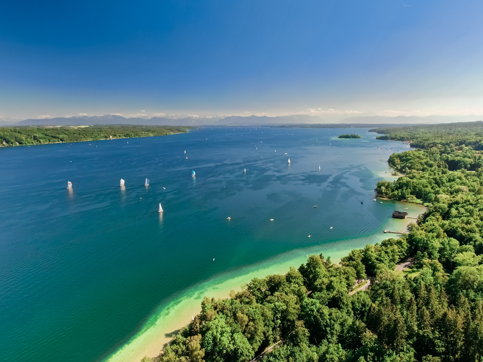 Drohnenaufnahme des Starnberger Sees mit Segelbooten und Alpenpanorama
