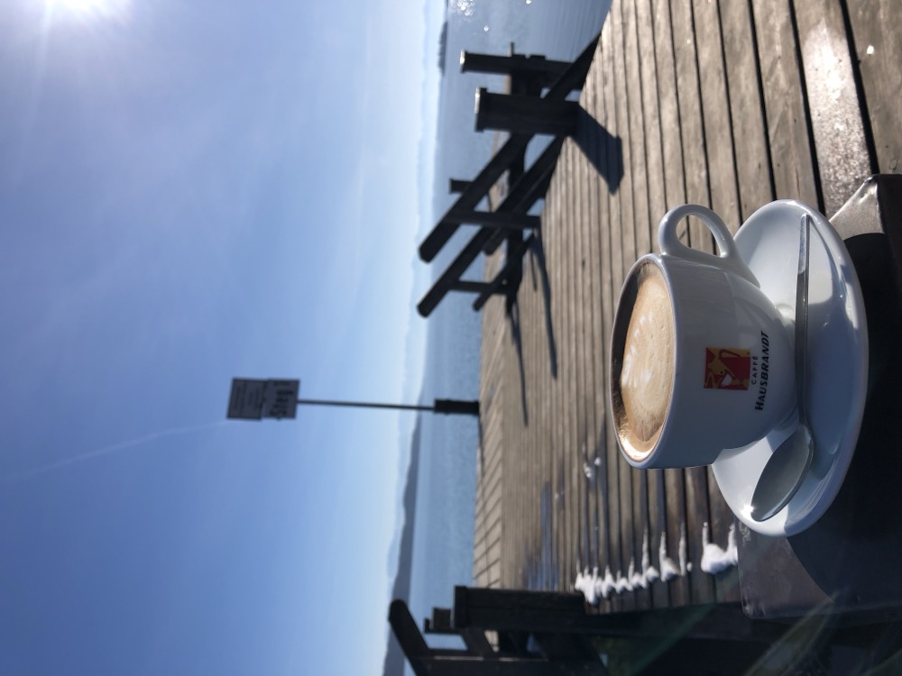 Cappuccino am Steg mit Sonnenstrahlen über dem See